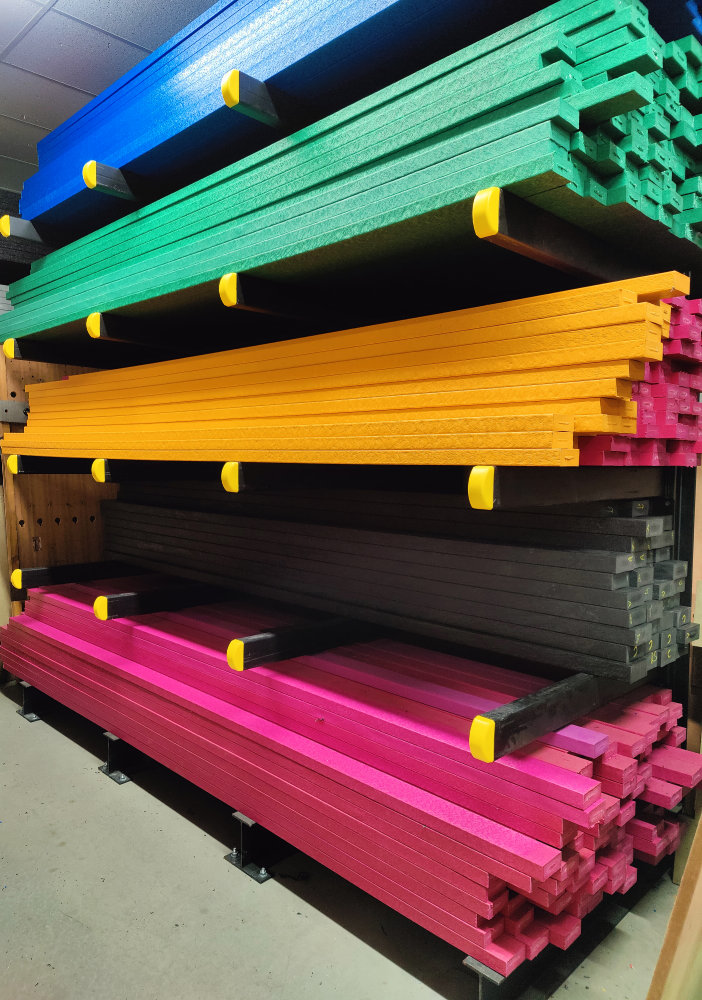 Brightly coloured recycled plastic lumber on a racking.